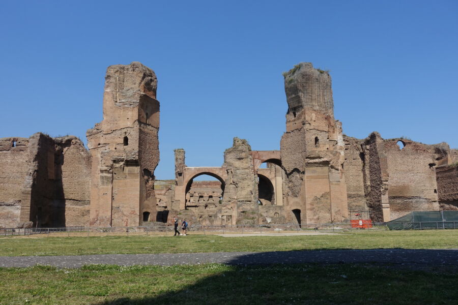 Two people stand in front of the Baths of Caracalla