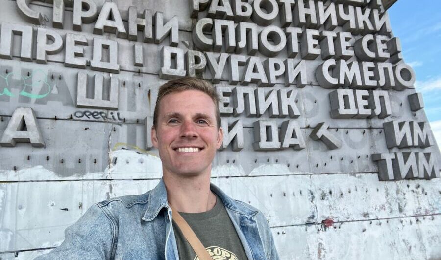 A smiling person standing before a wall in Bulgaria