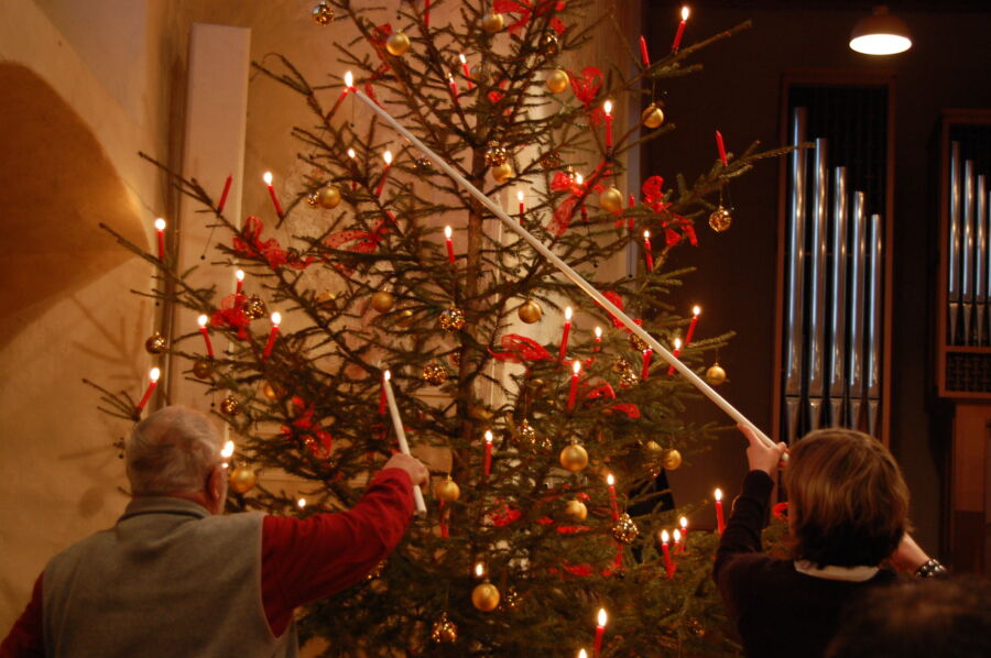 A family lights candles on a Christmas tree