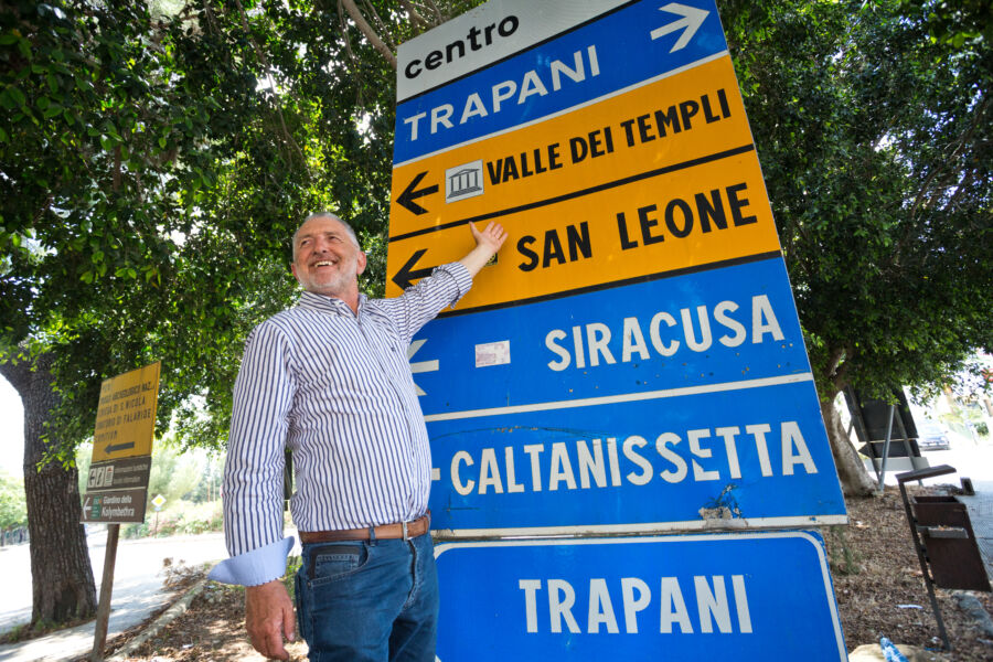 An Italian man pointing at a directional sign