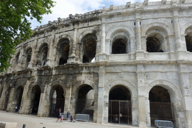 the outside of an ancient roman arena, half looks dirty and half looks clean