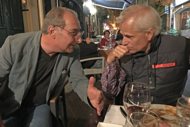 two men in an intense conversation over dinner