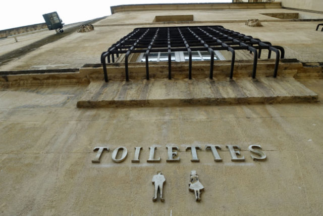 public bathroom sign on an older building