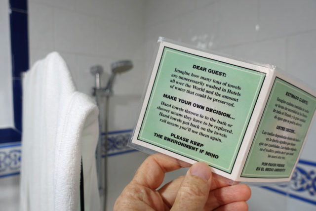 small sign in a bathroom asking guests to consider reusing towels