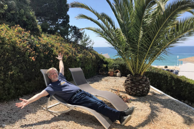 rick steves looking happy on a chair on the beach