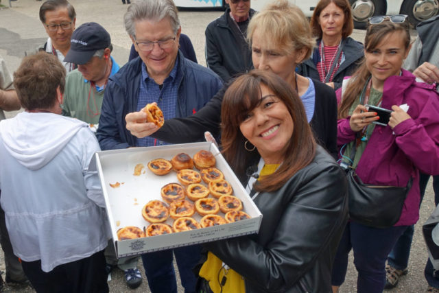 Fatima Bugarin smiling and holding a box of pasteis de belem, traditional Portuguese custard tarts