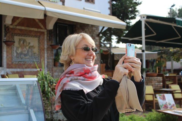 smiling woman taking a photo on her phone