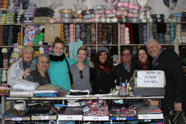 group of people smiling in a store selling yarn and fabric